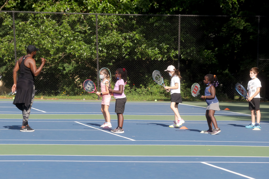 Four kids being instructed in tennis